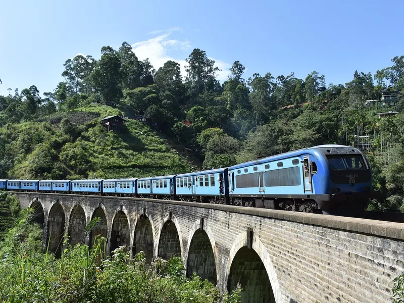 Een blauwe trein op de Nine Arch Bridge bij Ella